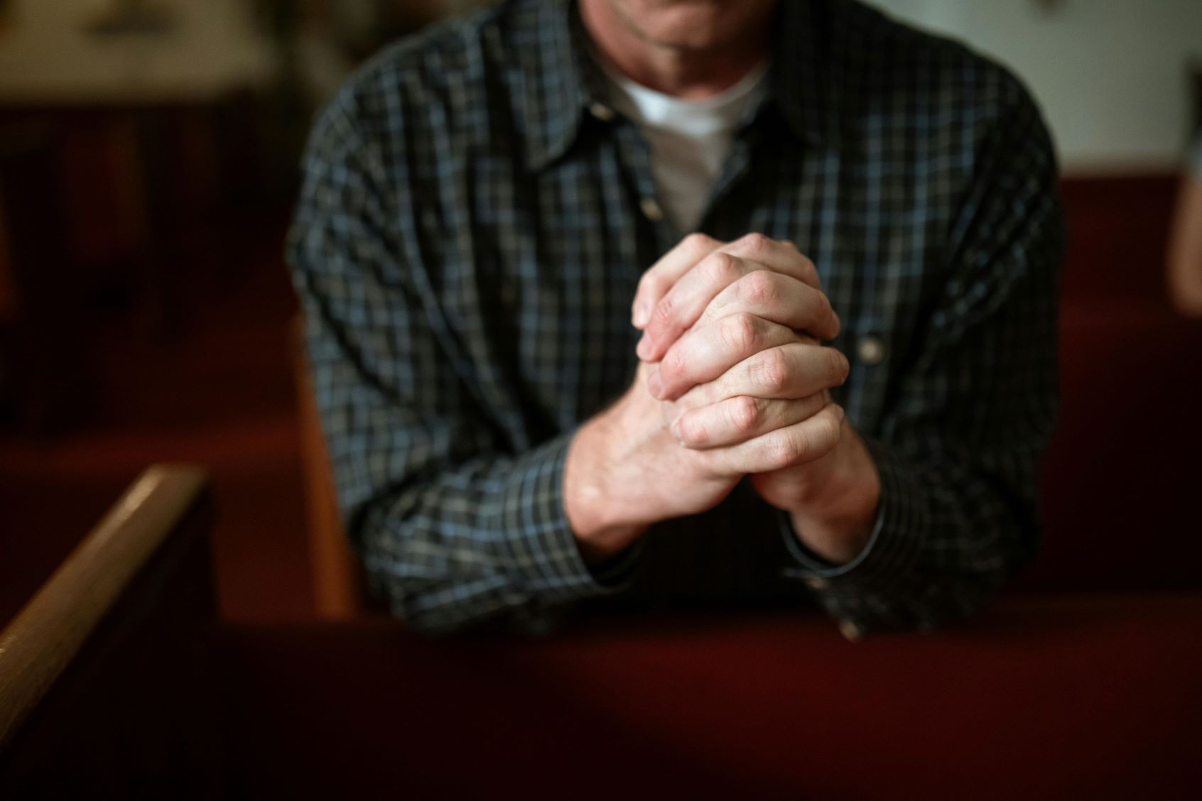 The promise of Heaven keeps Christians from despair. The upper torso, hands, and lower face of an adult, appearing to be male, are visible. They have a light skin tone.