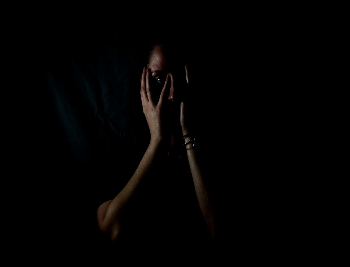 melanie-wasser-j8a-TEakg78-unsplash A woman standing alone in the dark, with her hands on her face looking frightened yet determined as her eyes continue to look ahead. Power Through Your Fears christian stories of faith