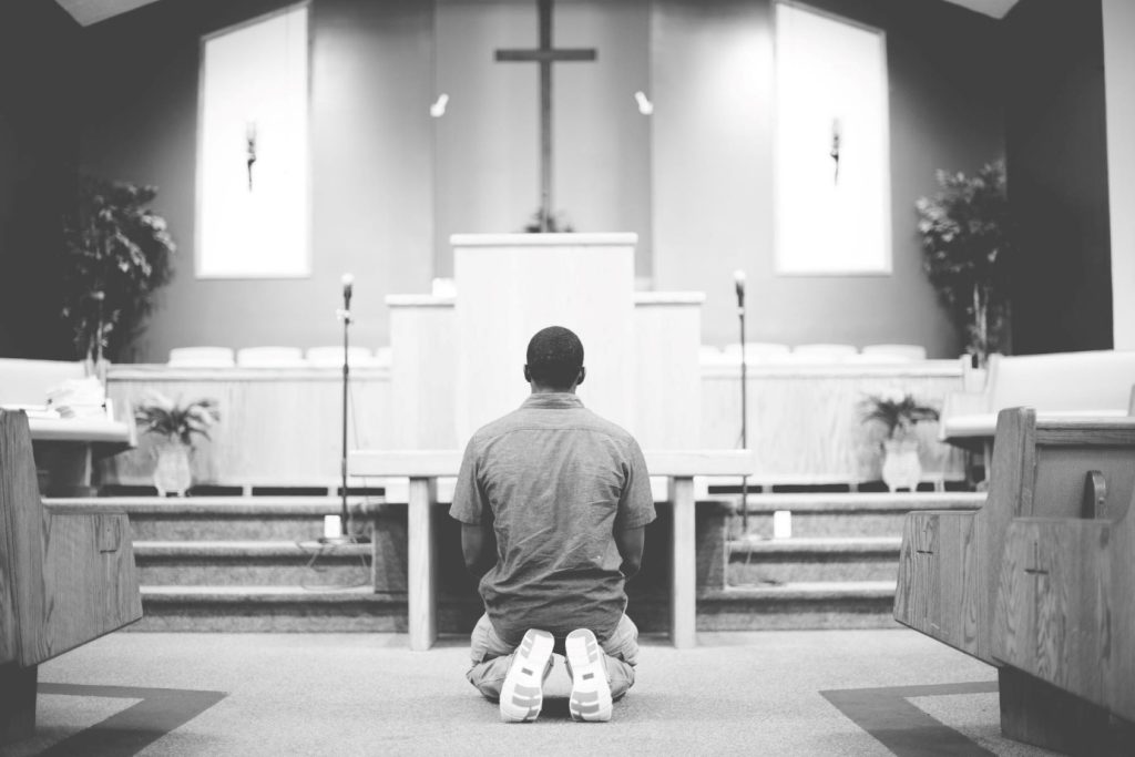 A man kneeling before an altar in church.