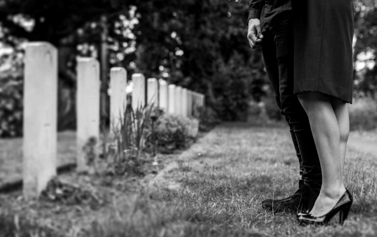 Consciousness transcends death and life. A couple standing near gravestones.