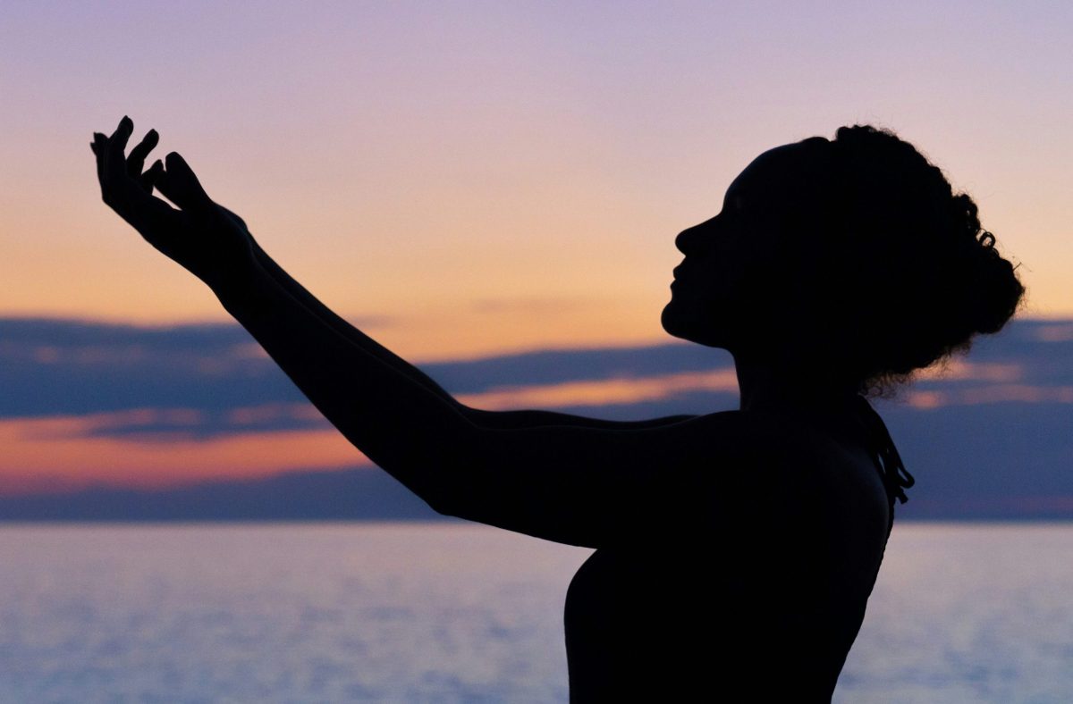 Image Source: Unsplash A woman is shown in profile, facing right, completely silhouetted against the bright background. Her hair is pulled up into a bun or similar style.