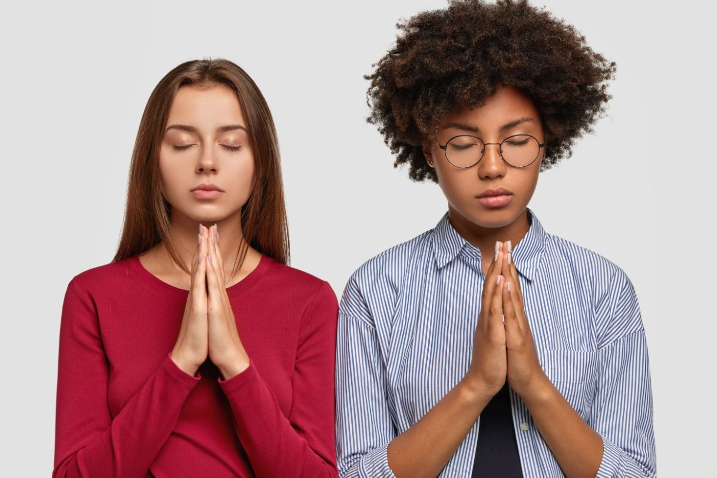 The Christian view on racism is that we are all one under God. A white woman and a black woman praying together.