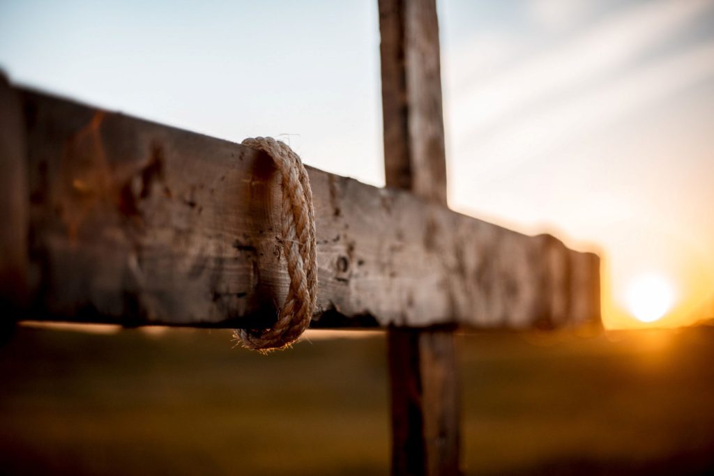 The fulcrum of a crucifix as the sun rises in the distance.
