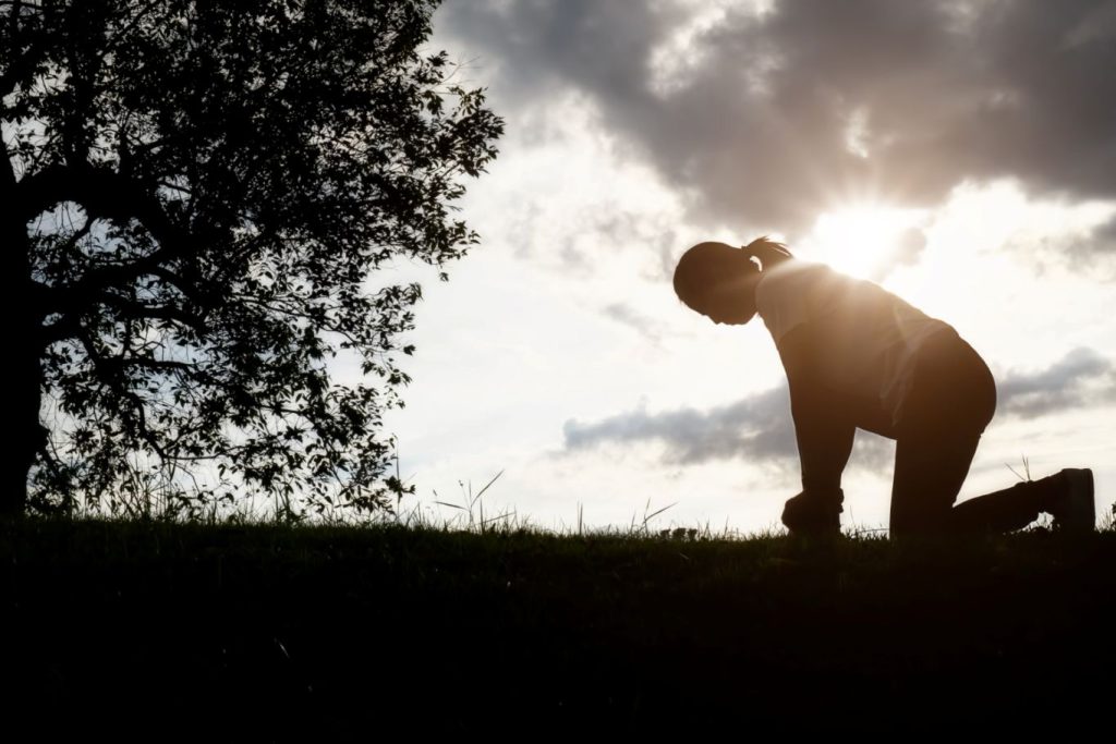 A person kneeling, having place her faith in God.