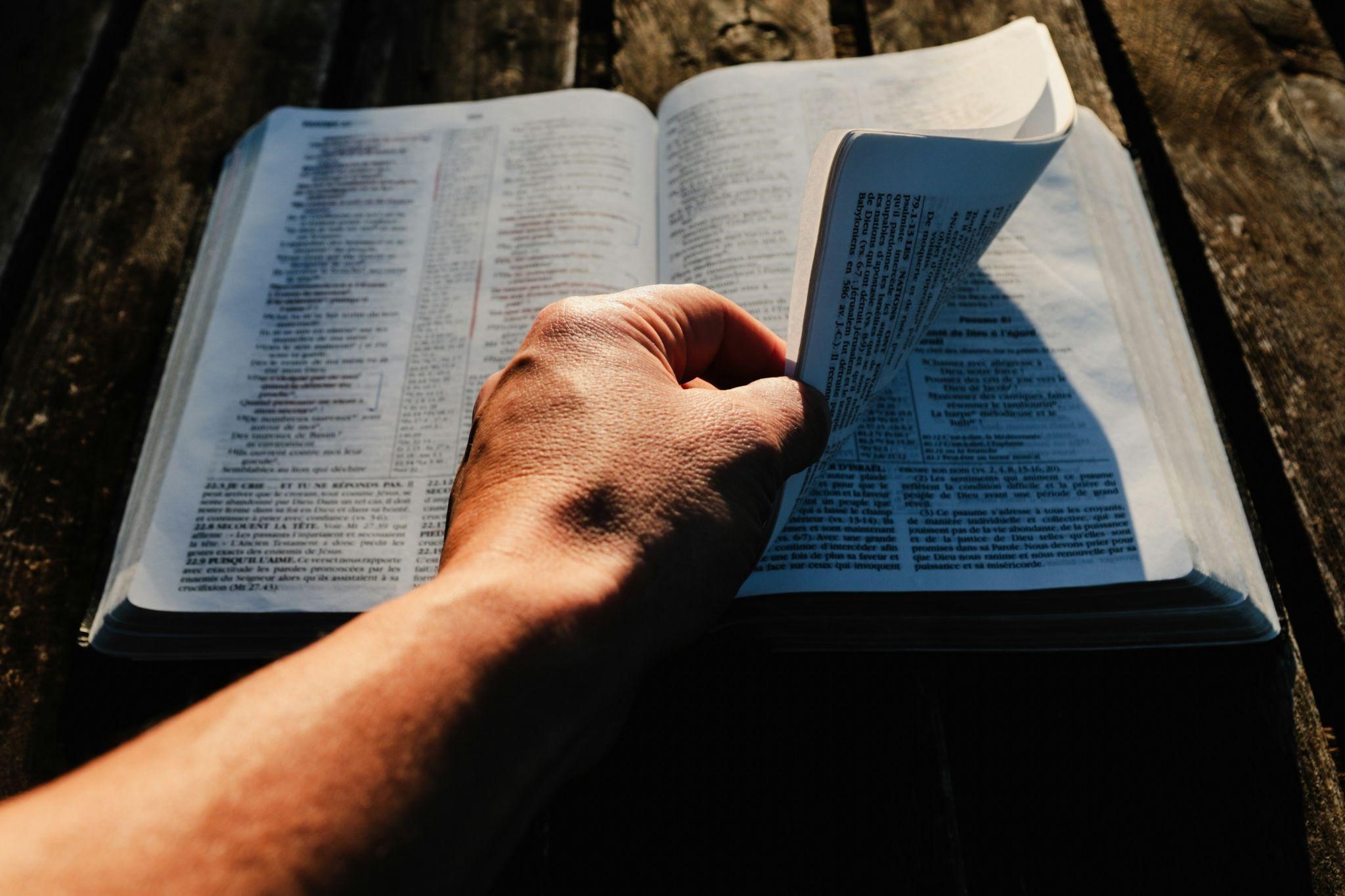 Daily Christian Living: Building Habits of Faith A hand turns a page in an open Bible, conveying daily Christian living.