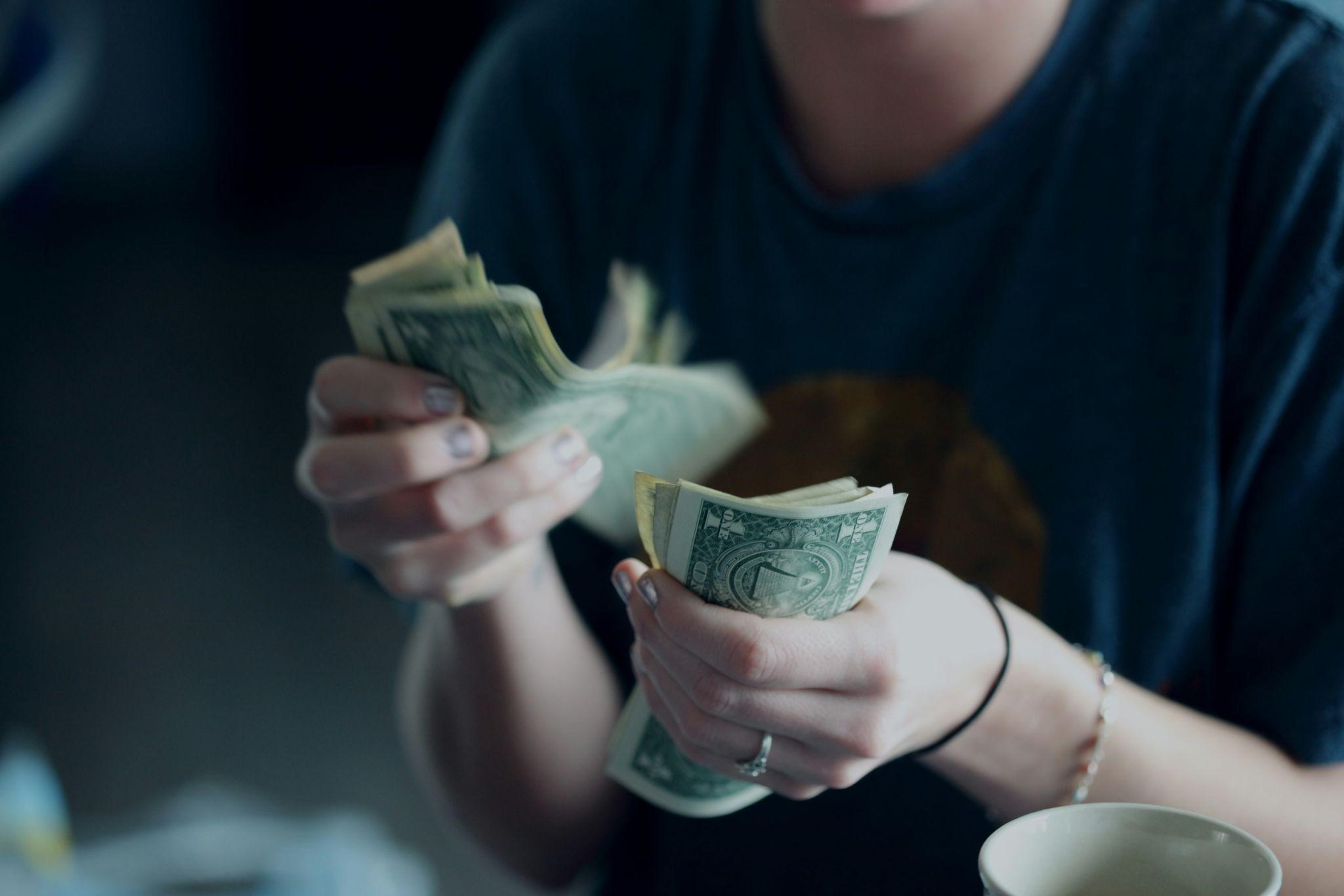 The Dangers of Worldly Living and How to Avoid Them A person is counting a stack of bills, conveying the dangers of worldly living.
