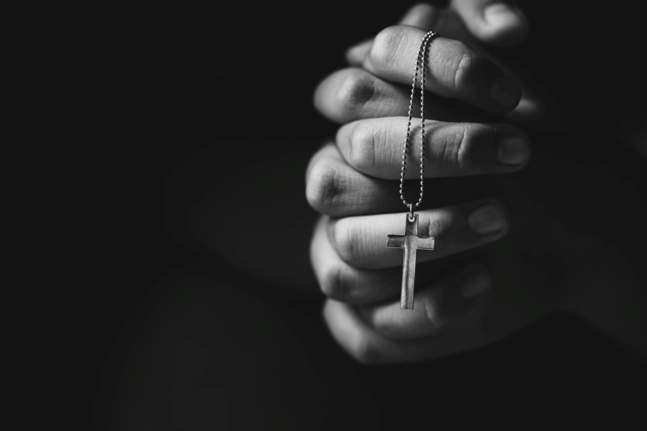Hands clutching a rosary tightly.