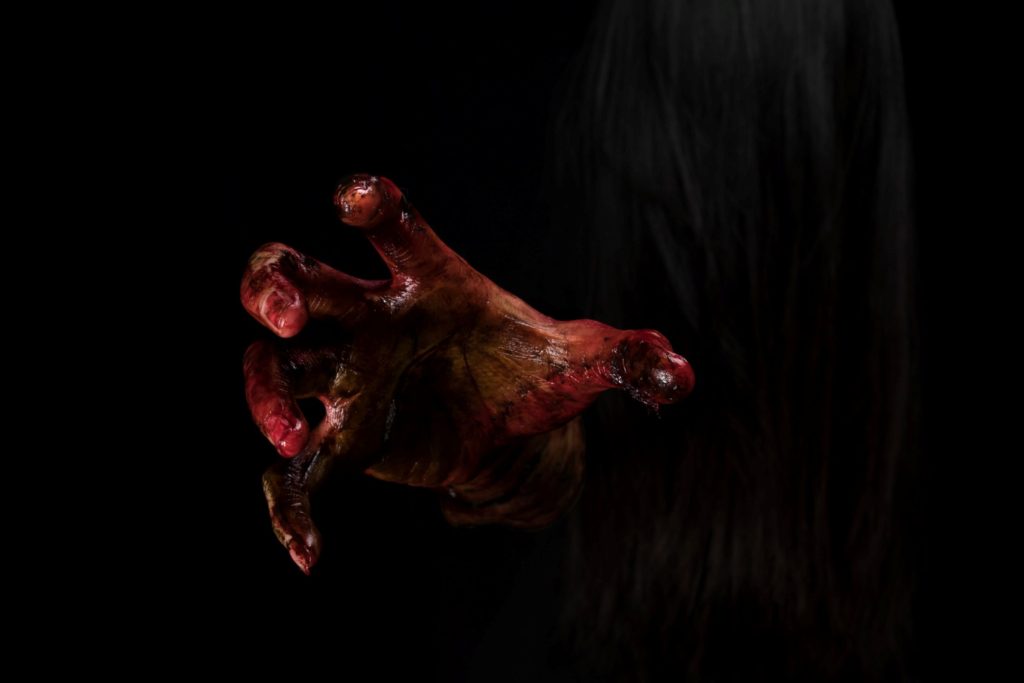 A bloody hand emerging from the shadows.