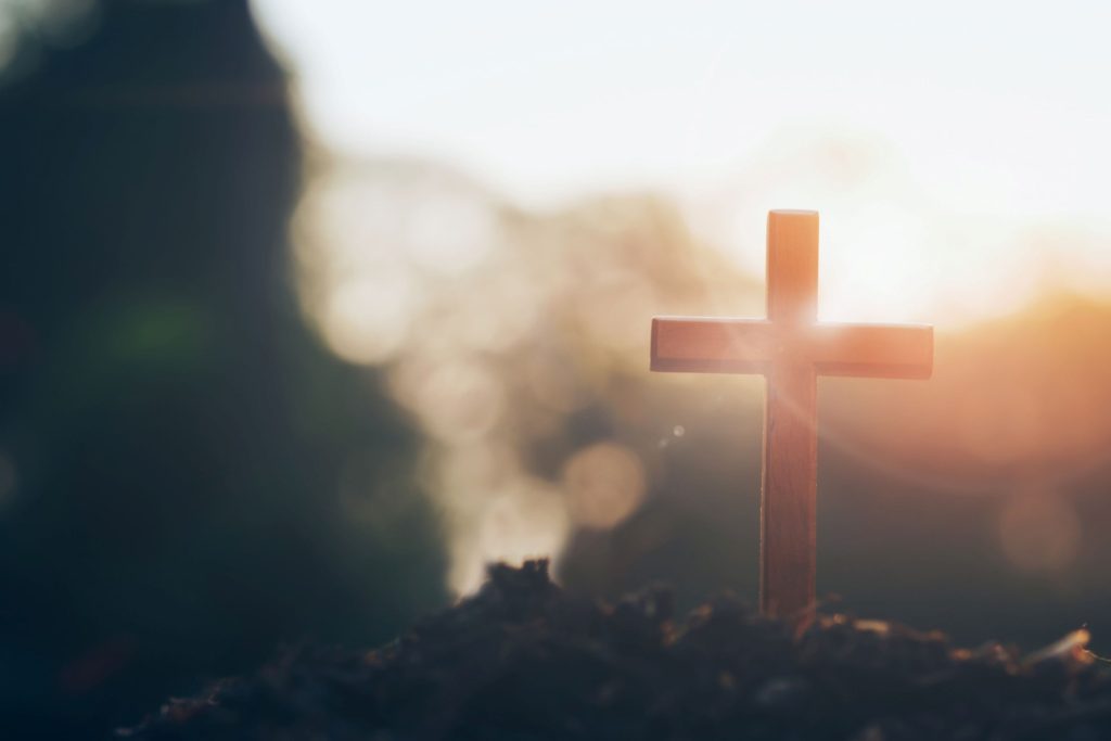 A small, wooden cross standing with the sunrise.